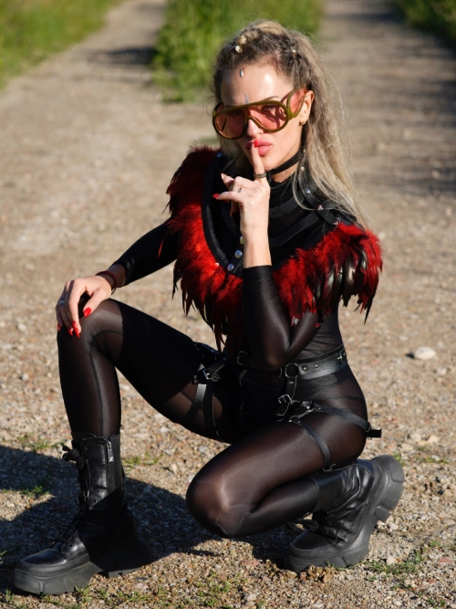 Danydeee in sunglasses and a black outfit crouching on a path