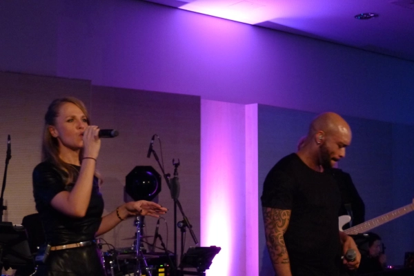 Danydeee singing with a band on a stage with purple lighting in Munich, Germany